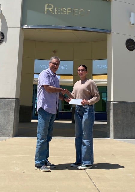 Man handing young woman a scholarship and shaking her hand