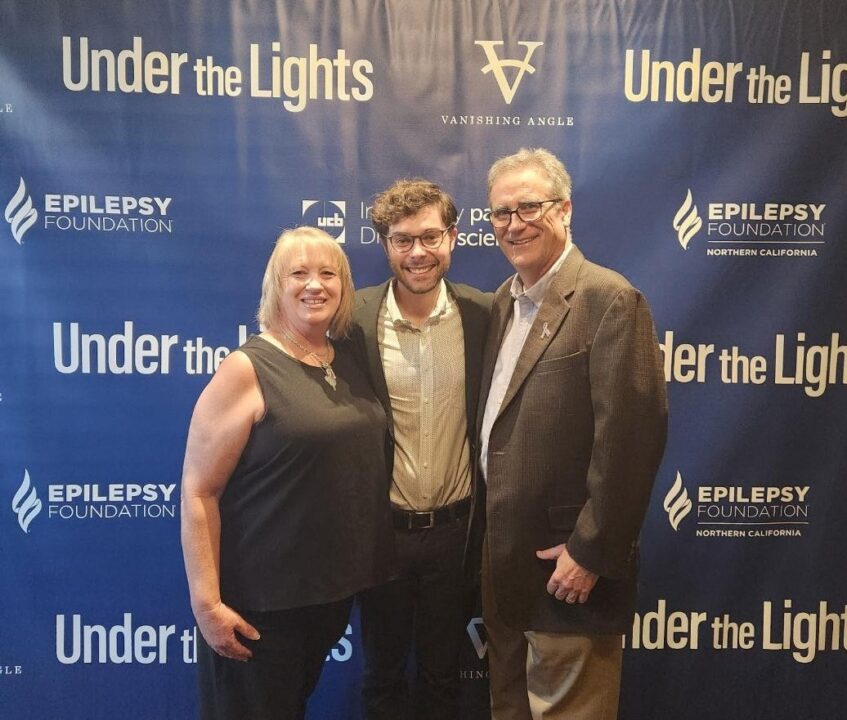 3 people in front of Under the Lights banner