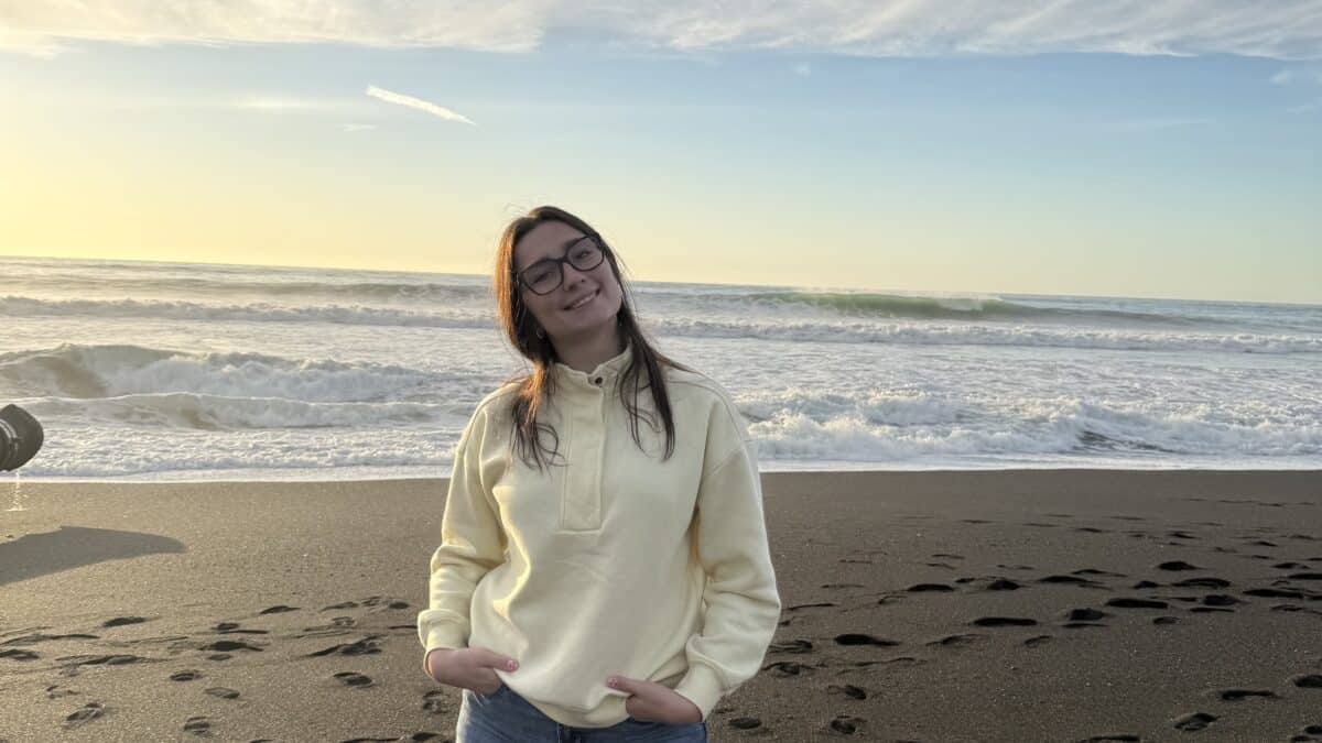 Young woman standing with white sweatshirt on the beach