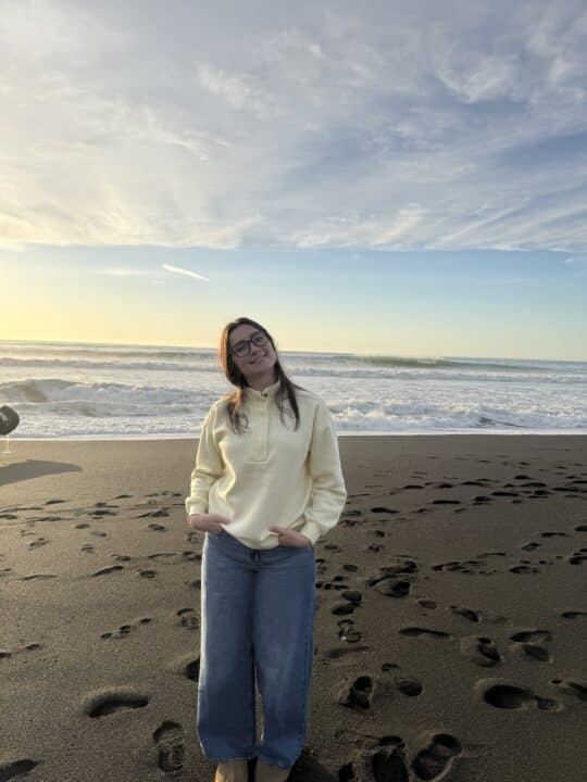 Young woman standing with white sweatshirt on the beach